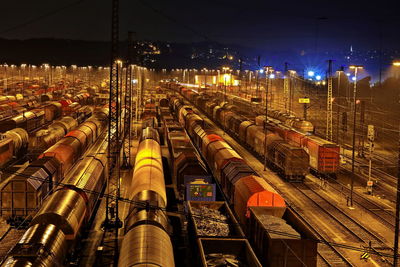 Train on illuminated railroad tracks against sky at night