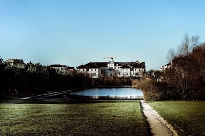 Building by trees against clear blue sky