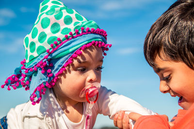 Close-up of siblings playing against sky