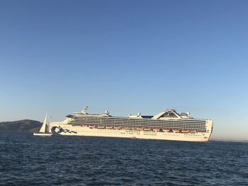 Ship sailing on sea against clear blue sky