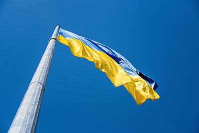 Ukrainian flag in the wind on blue sky background. large national yellow blue flag of ukraine. big