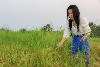 Young woman standing on field against sky