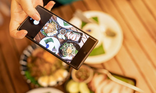 Midsection of person holding smart phone on table