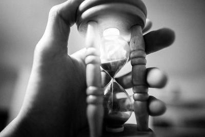 Close-up of hand holding clock against blurred background