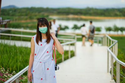 Woman standing on railing against blurred water