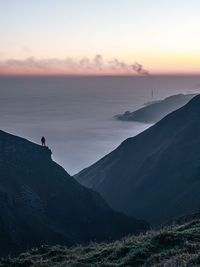 Silhouette man standing on mountain against sky during sunset