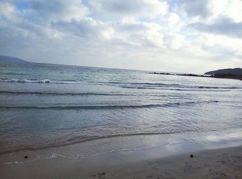 Scenic view of beach against cloudy sky