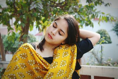 Young woman with eyes closed against trees 