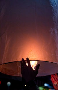 Close-up of silhouette hand holding sun against sky during sunset