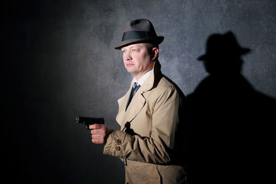 Man wearing hat standing against wall