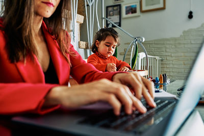 Woman using mobile phone while sitting in laptop