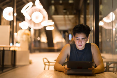 Man using mobile phone while sitting on table