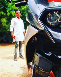 Portrait of young man standing by car