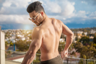 Midsection of shirtless man standing against sky