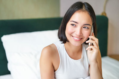 Portrait of young woman sitting on bed at home