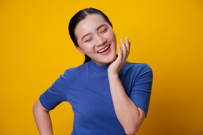 Portrait of a smiling young woman against yellow background