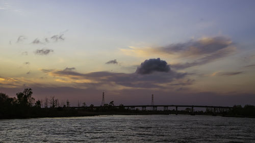 Silhouette bridge over sea against sky at sunset