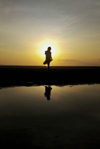 Silhouette man standing on beach against sky during sunset