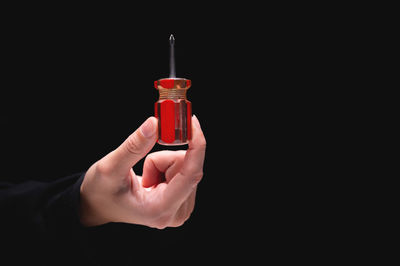 Cropped hand holding syringe against black background