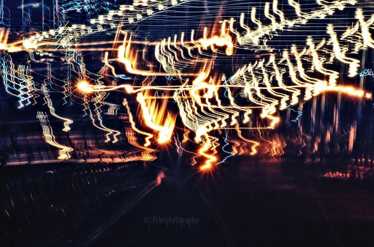 LIGHT TRAILS IN ILLUMINATED FIRE AT NIGHT