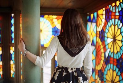 Rear view of woman standing against multi colored window