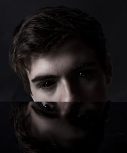 Close-up portrait of young man against black background