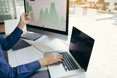 Midsection of businessman using laptop on table