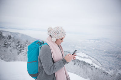 Man using phone while standing on snow covered landscape