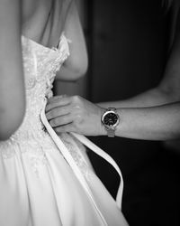 Midsection of bride holding wedding dress