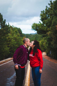 Young couple standing on road against trees and plants