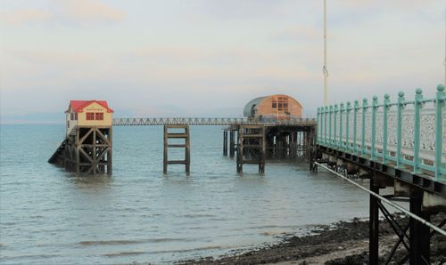 Pier and lifeboat station over sea against sky