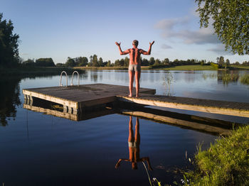 Man standing on jetty by swimming pool against lake