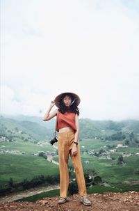 Full length of woman standing on mountain against sky