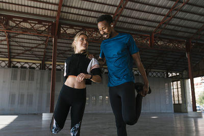 Male and female athletes doing warm up exercise in health club