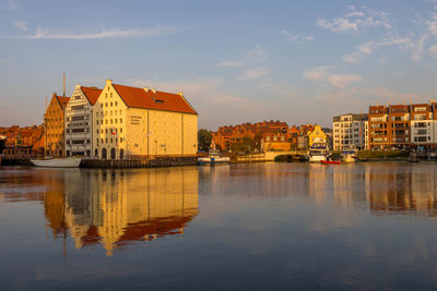 Buildings by river against sky in city