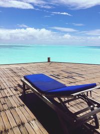 Chairs and table by swimming pool against sky