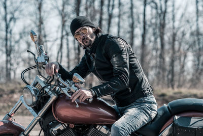 Mid adult man sitting on motorcycle in forest