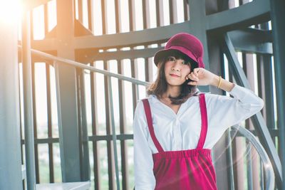 Portrait of woman standing against railing