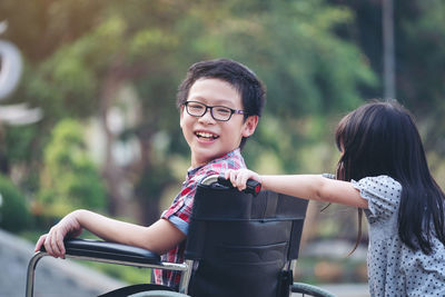 Portrait of happy boy sitting on wheelchair with sister