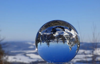 Close-up of crystal ball against blue sky
