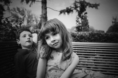 Portrait of smiling girl with brother sitting on bench