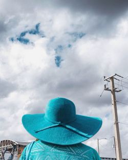 Rear view of woman wearing blue hat against cloudy sky