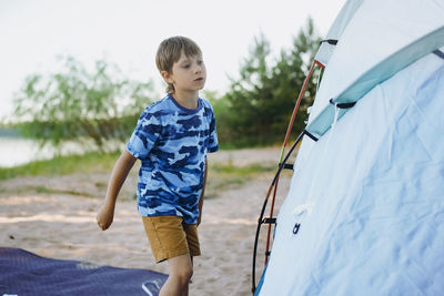 Cute little caucasian boy helping to put up a tent. family camping concept