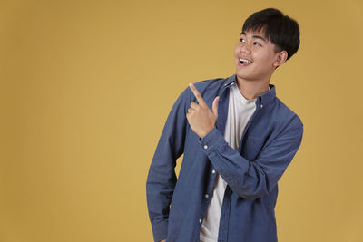 Young man looking away against yellow background