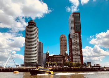 Modern buildings by river against sky in city