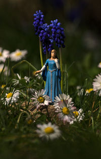 Close-up of purple statue by flower on field