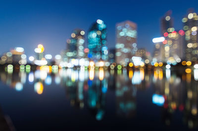 Defocused image of illuminated buildings against sky at night