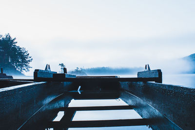 Empty bridge over calm sea against sky