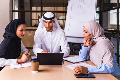 Portrait of young woman using laptop at office