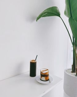 Close-up of coffee on table with potted plant at home